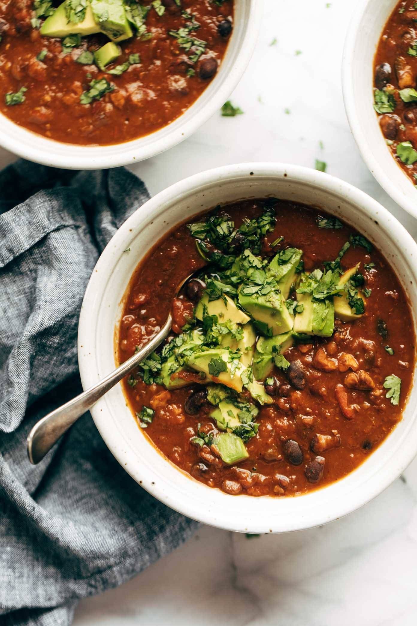 Pumpkin walnut chili in a bowl with avocado on top.