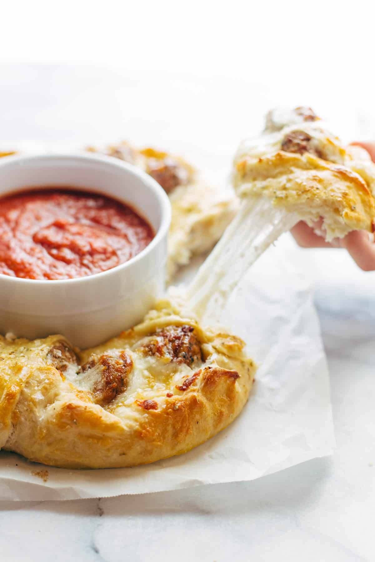 Pulling apart a meatball pizza ring.